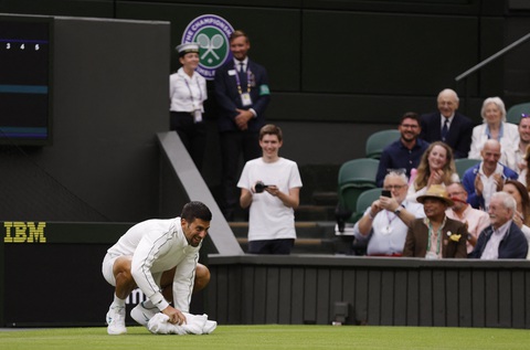 Djokovic, Swiatek 'tỏa sáng trong mưa' ở ngày mở màn Wimbledon 2023 - Ảnh 1. Djokovic khiến người hâm mộ khán đài cười rộ khi dùng khăn lau sân đấu - Ảnh: REUTERS