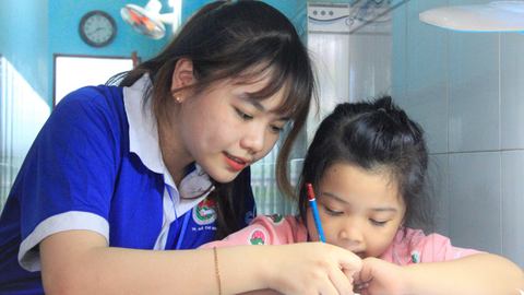 Lớp học với gia sư áo xanh - Ảnh 1. Cô giáo Anh Thy nắm tay tập viết cho một bạn nhỏ ở lớp học gia sư áo xanh tại khu lưu trú công nhân số 48 - Ảnh: CÔNG TRIỆU