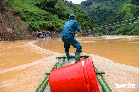 'Tích cóp cả đời mới xây được nhà, trong tích tắc lũ quét không còn thứ gì' - Ảnh 7. Lực lượng dân quân tự vệ dùng bè mảng đi qua suối Nậm Kim để tiếp tế lương thực, nhu yếu phẩm cho người dân bản Đề Sủa, xã Lao Chải