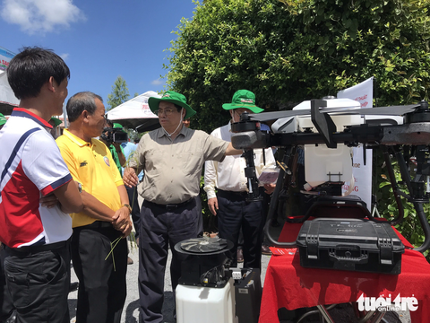 Thủ tướng ra đồng nói chuyện với nông dân miền Tây- Ảnh 4. Thủ tướng Phạm Minh Chính nghe nông dân giới thiệu các máy cơ giới công nghệ cao - Ảnh: ĐẶNG TUYẾT