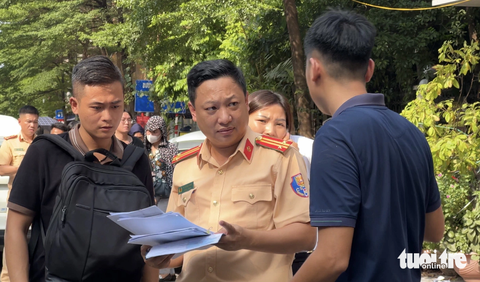 Đông nghịt người xếp hàng sang tên ô tô trước ngày biển số định danh có hiệu lực - Ảnh 5. Ngay từ ngoài cổng, nhiều cán bộ cảnh sát giao thông đứng hướng dẫn người dân vào làm thủ tục - Ảnh: DANH TRỌNG