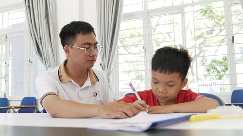 “Người cha, người anh” 26 tuổi của hàng chục trẻ em kém may mắn - Ảnh 1. Nguyễn Quang Hiếu hướng dẫn các em nhỏ học tập tại Trung tâm Nuôi dạy trẻ mồ côi Hoa Mai - Ảnh: Đ.H.