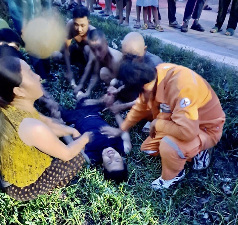 Một công nhân ngành điện dũng cảm lao ra dòng nước cứu người - Ảnh 1. Anh Nguyễn Tuấn Vũ (người nằm) sau khi đưa được người bị nạn lên bờ thì anh cũng kiệt sức. Trong ảnh là cảnh người dân và các đồng nghiệp đang tìm cách chăm sóc anh trước khi đưa vào bệnh viên cấp cứu - Ảnh: HƯƠNG NGUYÊN