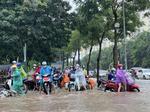Mưa như trút nước, đường phố Hà Nội ngập lênh láng - Ảnh 4. Do ngập sâu, đường phố ùn tắc nên nhiều người đi xe máy phải leo lên vỉa hè - Ảnh: PHẠM TUẤN