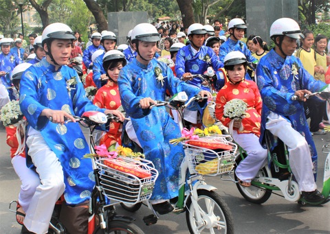 Mời cùng đăng ký dự lễ cưới tập thể TP.HCM 2023 - Ảnh 3. Các cô dâu, chú rể diễu hành bằng xe đạp điện qua một số tuyến đường trung tâm TP.HCM trước khi đến nơi tổ chức lễ cưới tập thể - Ảnh: Q.LINH
