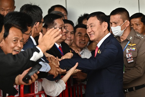 Ông Thaksin bắt tay người ủng hộ trước khi được đưa đến tòa án - Ảnh: AFP Ông Thaksin bắt tay người ủng hộ trước khi được đưa đến tòa án - Ảnh: AFP