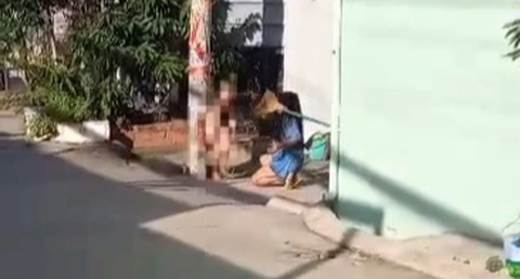 Hội Bảo vệ quyền trẻ em TP.HCM vào cuộc vụ bé trai 8 tuổi bị bạo hành - Ảnh 1. Bé trai trần truồng bị trói vào cột điện và bị người phụ nữ dùng chổi đánh - Ảnh cắt từ video do người dân ghi lại