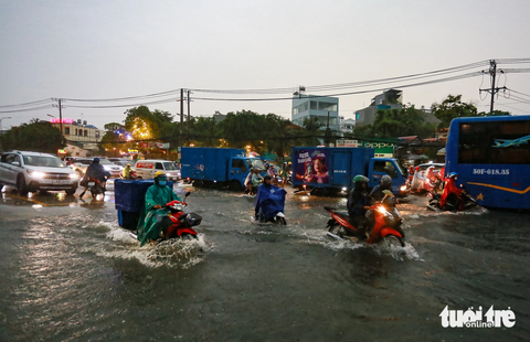 Nút thắt quốc lộ 13 chờ nghị quyết 98 'giải cứu' hiện tắc nghẽn ra sao? - Ảnh 5. Anh Đinh Thanh Hùng - người bán quán cơm trên đường - cho biết quốc lộ 13 nắng thì bụi bặm, mưa thì ngập. Nhiều xe bị ngập chết máy dẫn bộ lội nước, số khác thì chạy lên vỉa hè vì sợ sóng nước xô ngã. "Hàng quán xung quanh cũng khổ theo, chúng tôi nghe dự án mở rộng đường hơn 20 năm rồi nhưng chưa thấy làm", anh Hùng nói.