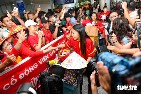 Huỳnh Như khóc khi về nước, hy vọng tuyển nữ Việt Nam sẽ lại được dự World Cup - Ảnh 1. Huỳnh Như và các đồng đội được đông đảo người hâm mộ đón chào ở sân bay Nội Bài - Ảnh: NAM TRẦN