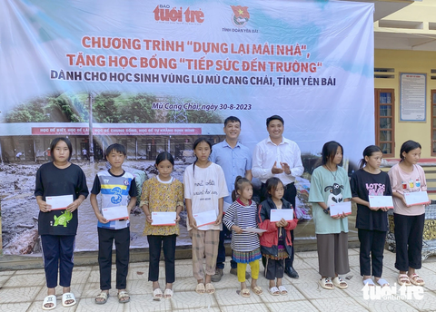 10 sổ tiết kiệm, 52 suất học bổng trị giá hàng trăm triệu đồng cho vùng lũ Mù Cang Chải - Ảnh 6. Đại diện báo Tuổi Trẻ và Huyện Đoàn Mù Cang Chải trao học bổng cho các em học sinh - Ảnh: NGỌC QUANG