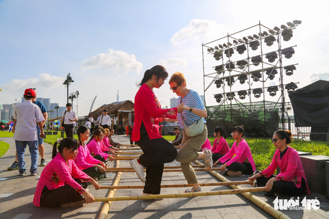 Trò chơi dân gian, buýt đường sông... hấp dẫn du khách quốc tế - Ảnh 1. Du khách người Anh trải nghiệm trò chơi dân gian nhảy sạp ở công viên Bến Bạch Đằng - Ảnh: PHƯƠNG QUYÊN