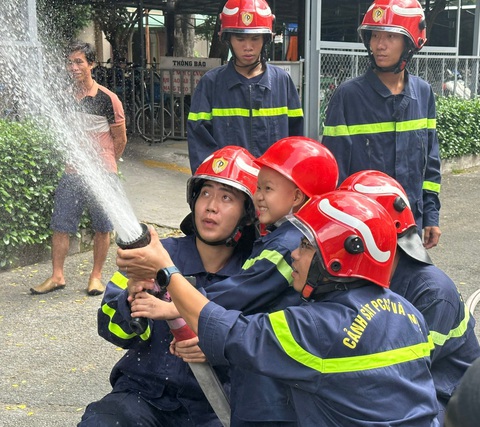 Cậu bé mắc ung thư cười khoái chí được làm lính cứu hỏa - Ảnh 1. Bé Trung Quân cười khoái chí khi cùng các chiến sĩ Phòng Cảnh sát phòng cháy chữa cháy và cứu nạn cứu hộ (PC07) Công an TP.HCM cầm lăng phun "chữa cháy" - Ảnh: BVCC