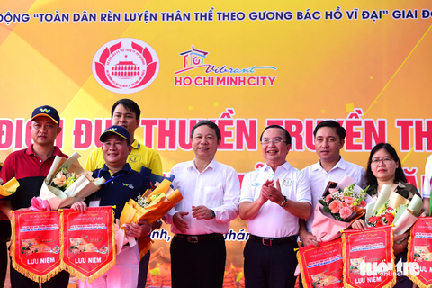 Sôi động tranh tài đua thuyền tại Lễ hội Sông nước TP.HCM - Ảnh 3. Ông Dương Anh Đức, phó chủ tịch UBND TP.HCM (giữa) và ông Trần Thế Thuận, giám đốc Sở Văn hóa và Thể thao TP.HCM trao cờ lưu niệm cho các đội đua