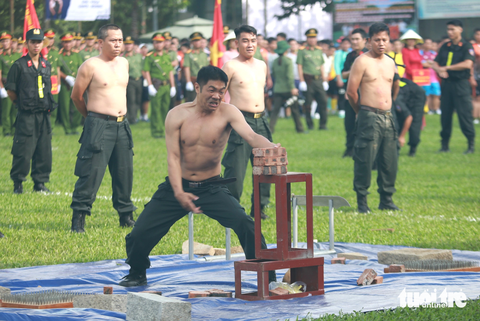Chiến sĩ công an biểu diễn bài dùng tay &quot;chặt&quot; bể ba cục gạch - Ảnh: MINH HÒA