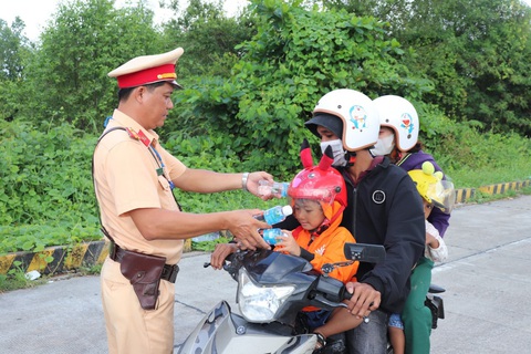 Cảnh sát giao thông Sóc Trăng hỗ trợ áo mưa, xăng… cho người dân về quê nghỉ lễ Quốc Khánh - Ảnh 1. Người dân về quê nghỉ lễ được cảnh sát giao thông Sóc Trăng trao nước uống dọc đường - KHẮC TÂM