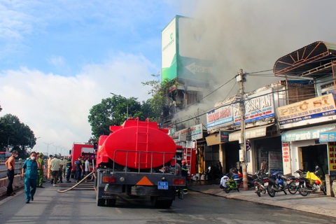 Hai tiệm bán phụ tùng ô tô dọc quốc lộ 1 bốc cháy dữ dội - Ảnh 3. Nhiều xe chuyên dụng được điều đến hiện trường để dập lửa - Ảnh: AN BÌNH