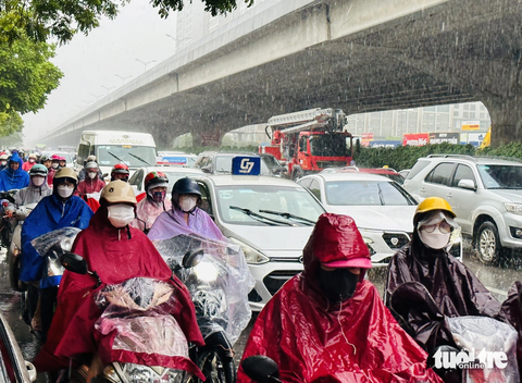 Mưa tầm tã vào đúng giờ đi làm, đường phố Hà Nội hỗn loạn, ùn tắc - Ảnh 1. Người Hà Nội đội mưa đi làm trong cơn mưa tầm tã - Ảnh: QUANG VIỄN