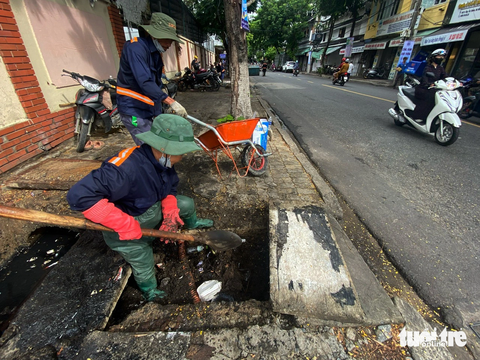 Cả chục ký bao ni lông dưới cửa thu nước trên đường phố Đà Nẵng thì thoát nước thế nào? - Ảnh 2. Công nhân Công ty Thoát nước và Xử lý nước thải Đà Nẵng dọn vệ sinh hố thu nước ở các tuyến đường trung tâm - Ảnh: TRƯỜNG TRUNG