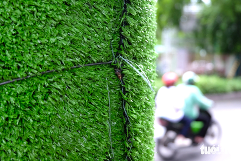 'Trồng cỏ' trên cột đèn, cột điện để trị dán quảng cáo sai quy định - Ảnh 2. Những thảm cỏ nhân tạo này được cố định quanh các cột đèn, cột điện bằng kẽm tương đối chắc chắn. Người dân cho biết địa phương cũng thường xuyên kiểm tra và thay mới chúng khi có hư hỏng, nhưng thời gian gần đây lại xuất hiện những tờ quảng cáo, rao vặt dán sai quy định