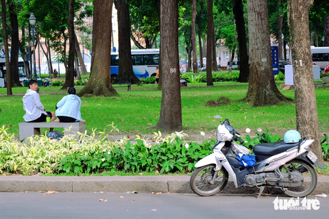 Thiếu bãi giữ xe công viên, TP.HCM chỉ đạo khẩn - Ảnh 1. Người đàn ông ngồi hóng mát trong công viên 30 Tháng 4 (quận 1) vẫn không quên quan sát xe mình đậu dưới lòng đường - Ảnh: PHƯƠNG NHI