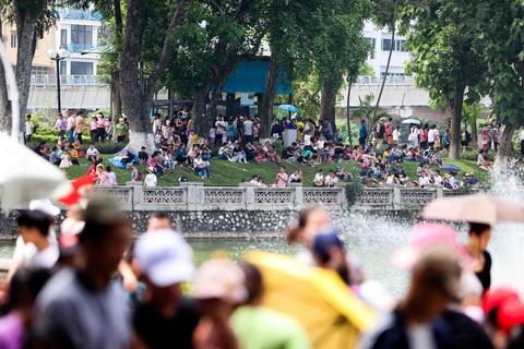 Hà Nội ngày 2-9: khu vui chơi đông nghẹt, cửa ngõ thông thoáng - Ảnh 3. Thời tiết Hà Nội khá oi nóng, nhiệt độ gần trưa lên đến 37, 38 độ C, nhiều người phải ngồi trên thảm cỏ để tránh nóng - Ảnh: NGUYỄN KHÁNH