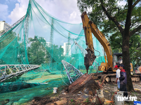 Hàng loạt trụ sắt rào lưới sân golf và cây xanh ở TP.HCM bị dông lốc quật ngã - Ảnh 1. Các nhân công tháo dỡ trụ sắt bị gió mạnh quật ngã - Ảnh: NGỌC KHẢI