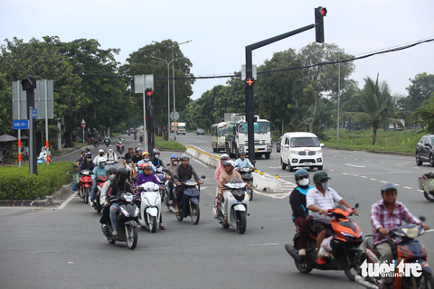 Vòng xoay Nguyễn Văn Linh liên tục tai nạn chết người, vì sao? - Ảnh 3. Xe lớn từ đường Nguyễn Văn Linh dừng đèn đỏ, để xe máy đi thẳng khi đèn xanh, không còn xung đột hướng như trước - Ảnh: MINH HÒA