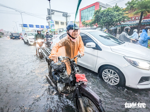 Áp thấp nhiệt đới gây mưa lớn, Đà Nẵng ngập nhiều nơi - Ảnh 1. Một thanh niên dắt xe qua đoạn ngập trên đường Tôn Đức Thắng do xe ngập nước chết máy - Ảnh: TẤN LỰC