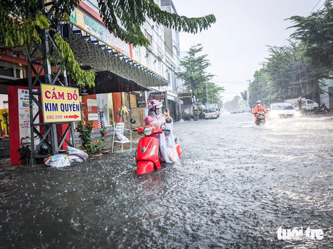 Áp thấp nhiệt đới gây mưa lớn, Đà Nẵng ngập nhiều nơi - Ảnh 2. Người phụ nữ gọi điện thoại cầu cứu người thân vì xe bị ngập nước chết máy khi vào đường Tôn Đức Thắng - Ảnh: TẤN LỰC