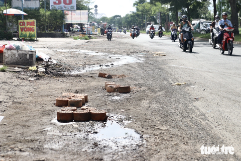 Đường Nguyễn Văn Linh hư hỏng nặng: Dân sụp 'ổ gà' ngã nhào - Ảnh 4. Có những đoạn người dân dùng gạch đá, than tổ ong lấp tạm điểm trũng để cảnh báo người đi đường không đi vào - Ảnh: TIẾN QUỐC
