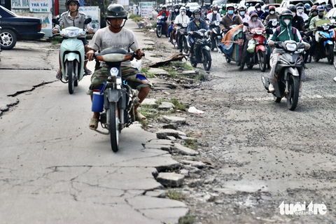 Đường Nguyễn Văn Linh hư hỏng nặng: Dân sụp 'ổ gà' ngã nhào - Ảnh 5. Vỉa hè bong tróc, vỡ vụn, còn người dân thì thường xuyên leo lề vào giờ cao điểm - Ảnh: TIẾN QUỐC