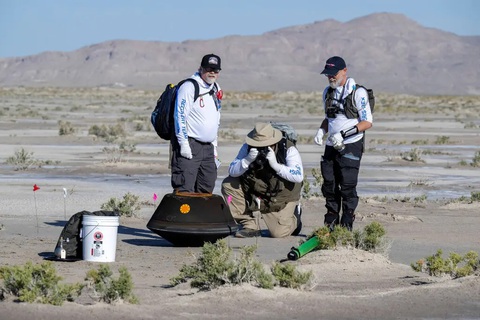 Mẫu vật tiểu hành tinh đầu tiên do NASA mang về Trái đất - Ảnh 1. Các nhà nghiên cứu bên cạnh khoang chứa mẫu vật từ tiểu hành tinh Bennu của NASA đáp xuống sa mạc ở Utah, Mỹ ngày 24-9 - Ảnh: THE NEW YORK TIMES