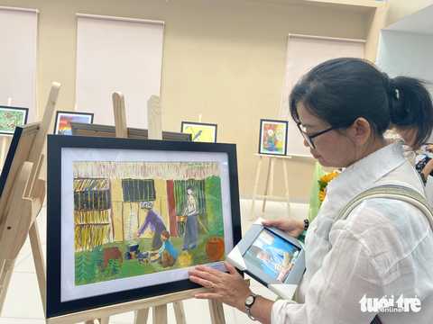 Triển lãm tranh bệnh nhân: Người vợ xúc động ngắm ảnh của người chồng đã qua đời - Ảnh 1. Chị Đoàn Nguyên Thùy xúc động khi nhìn lại những bức tranh do chồng mình - anh Phạm Minh Đức - vẽ bằng tay trái khi còn sống. Trước khi phát hiện ung thư phổi giai đoạn 4 (và qua đời sau đó), anh Phạm Minh Đức từng bị tai biến mạch máu não 10 năm - Ảnh: XUÂN MAI