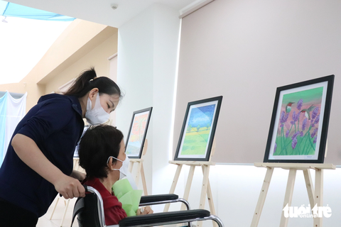 Triển lãm tranh bệnh nhân: Người vợ xúc động ngắm ảnh của người chồng đã qua đời - Ảnh 3. Bệnh nhân được người nhà đưa đến buổi triển lãm ngắm nhìn bức tranh do chính tay mình vẽ - Ảnh: XUÂN MAI