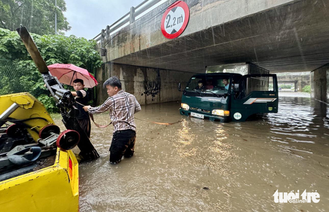Đường phố Hà Nội ngập sâu vì mưa to, trời tối mịt như ban đêm - Ảnh 10. Một chiếc xe tải chết máy đang được xe cứu hộ giải cứu, ảnh chụp tại đường giao cắt Đại lộ Thăng Long - Ảnh: NGUYỄN KHÁNH