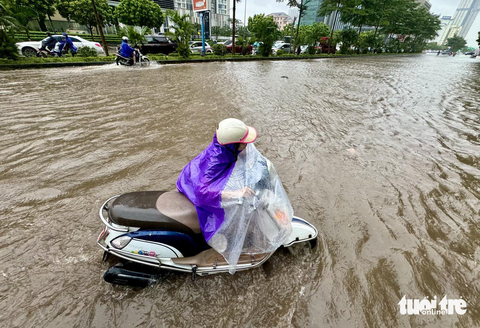 Đường phố Hà Nội ngập sâu vì mưa to, trời tối mịt như ban đêm - Ảnh 8. Một phụ nữ vất vả đẩy chiếc xe bị chết máy giữa khu vực bị ngập tại nút giao Dương Đình Nghệ - Phạm Hùng - Ảnh: NGUYỄN KHÁNH
