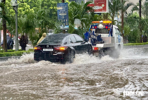 Đường phố Hà Nội ngập sâu vì mưa to, trời tối mịt như ban đêm - Ảnh 9. Một chiếc ô tô bị chết máy đang được xe cứu hộ cẩu đi - Ảnh: NGUYỄN KHÁNH