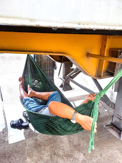 Nỗi niềm đời tài xế container đường dài - Kỳ 2: Vật vã đợi giao hàng nơi biên giới Móng Cái - Ảnh 2. Tài xế mệt mỏi, mắc võng ngủ thiếp ngay dưới gầm xe ở biên giới Móng Cái - Ảnh TRƯƠNG NHẤT VƯƠNG