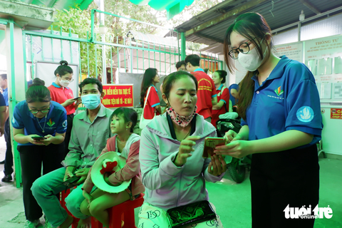 Trưởng thành và nhiều trải nghiệm từ phong trào tình nguyện - Ảnh 1. Sinh viên hỗ trợ người dân tại huyện Bình Chánh, TP.HCM khi đến cài đặt mã định danh điện tử - Ảnh: K.ANH