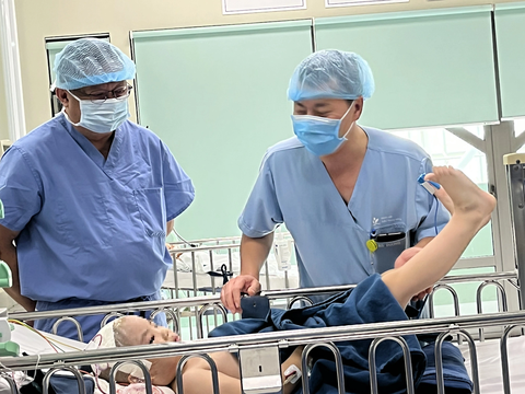 Lần đầu tiên tại Việt Nam đặt điện cực vỏ não điều trị cho trẻ em mắc động kinh kháng thuốc - Ảnh 1. Bác sĩ Thắng (bên trái) và cộng sự thăm bệnh nhi sau ca phẫu thuật - Ảnh: HỒNG HÀ