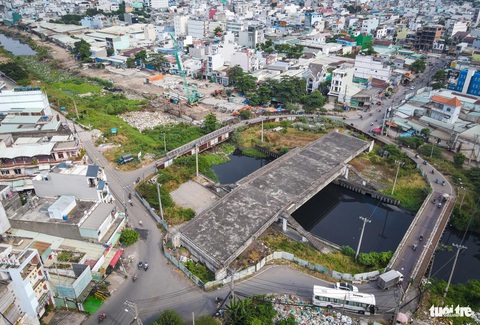Trên công trường cải tạo kênh dài nhất TP.HCM ngày đầu năm 2024- Ảnh 7. Một tổ xây dựng túc trực tại gói XL5, sát bên là cầu Tân Kỳ - Tân Quý (quận Bình Tân) bắc qua kênh Tham Lương đang xây dựng dang dở, hai bên là cầu tạm bằng sắt để người dân đi tạm thời - Ảnh: CHÂU TUẤN