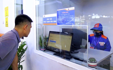 Người mua hàng đối chiếu thông tin để phát hành hóa đơn điện tử sau khi mua hàng tại một cửa hàng xăng dầu - Ảnh: N.KH. Người mua hàng đối chiếu thông tin để phát hành hóa đơn điện tử sau khi mua hàng tại một cửa hàng xăng dầu - Ảnh: N.KH.
