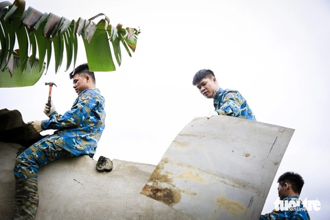 Quân đội đến sửa nhà dân bị hư sau vụ rơi máy bay Su-22- Ảnh 1. Chiến sĩ Sư đoàn không quân 372 sửa chữa mái tôn nhà dân bị hư hại sau vụ rơi máy bay Su-22 tại thị xã Điện Bàn, tỉnh Quảng Nam - Ảnh: C.S.