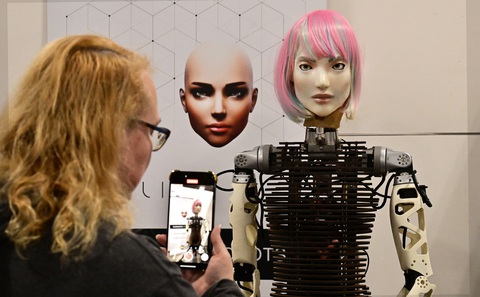 Một phụ nữ chụp ảnh cùng mô hình robot AI ở Hội chợ điện tử tiêu dùng (CES) tại thành phố Las Vegas (Mỹ) ngày 10-1 - Ảnh: AFP Một phụ nữ chụp ảnh cùng mô hình robot AI ở Hội chợ điện tử tiêu dùng (CES) tại thành phố Las Vegas (Mỹ) ngày 10-1 - Ảnh: AFP