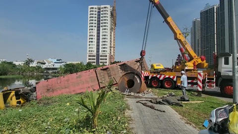 Xe container chở cuộn thép ủi văng dải phân cách, lao xuống hồ nước ven đường- Ảnh 2. Lực lượng chức năng xử lý hiện trường - Ảnh: NHẬT LỆ