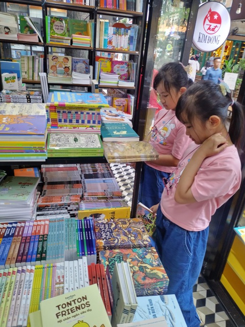 Đặt điện thoại xuống, cầm sách lên: Để thói quen đọc sách len lỏi vào mỗi nhà- Ảnh 3. Hằng tháng, Ngọc Khuê - Ngân Khuê (Q.Gò Vấp) được ba mẹ đưa đến Đường sách TP.HCM để thỏa thích chọn đọc những cuốn sách mới - Ảnh: C.D.
