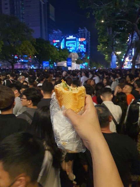 Chàng trai countdown cùng... ổ bánh mì nhận ngàn lời khen- Ảnh 1. Check-in đêm giao thừa ở phố đi bộ cùng với ổ bánh mì gặm dở.
