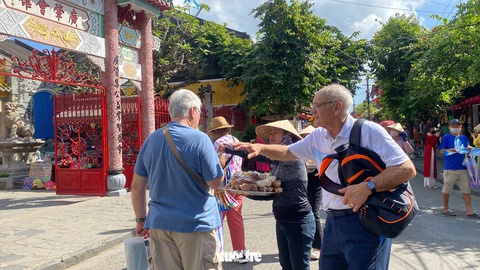 Hàng rong đeo bám chặn đường ép du khách ở Hội An- Ảnh 2. Thấy bạn mình bị hàng rong chèo kéo, làm phiền nên người khách đi cùng phải kéo vai