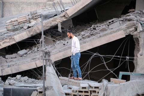 Giao tranh bất ngờ rộng khắp Dải Gaza, gần 500 người thương vong- Ảnh 1. Một người đàn ông đứng trên đống đổ nát sau khi quân đội Israel đột kích thành phố Hebron, thuộc khu vực Bờ Tây hôm 21-1 - Ảnh: AFP