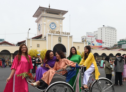 Kiều bào du xuân, tour Tết 'đông cực kỳ'- Ảnh 5. Thế hệ trẻ sinh ra từ nước ngoài được phụ huynh cho mặc áo dài chụp ảnh trước chợ Bến Thành, một trong các biểu trưng của TP.HCM - Ảnh: TỰ TRUNG